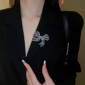 Detail of zircon bow brooch with purple and green crystals pinned on black blazer
