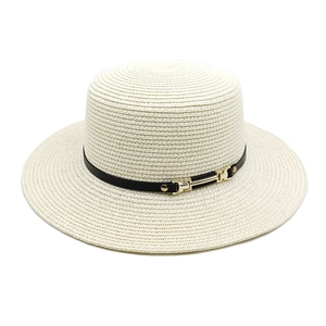 Détail d'un chapeau de paille à large bord avec ruban en cuir noir et boucle dorée