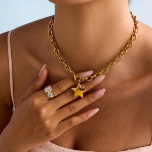 Detail of chunky gold chain necklace with star pendant and rose floral ring on model