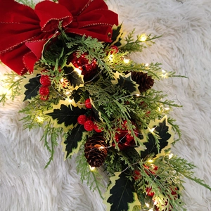 Close-up of lit LED Christmas teardrop swag with red berries and pine cones