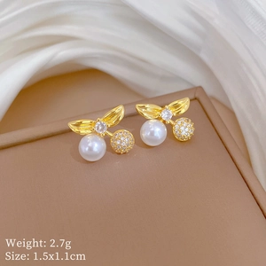 Macro detail of gold cherry earrings with white pearls and sparkling pavé crystals