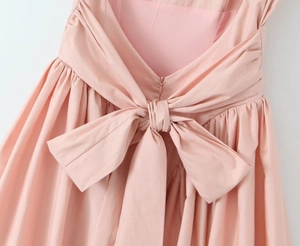 Detail of pink dress back featuring a large bow and hidden zipper closure