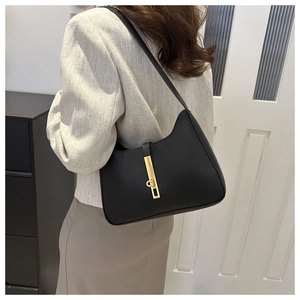 Detail of minimalist black leather underarm bag with a golden bar metal lock buckle