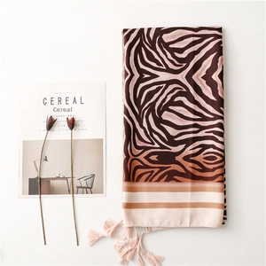 Detail of brown zebra print scarf with beige fringe and tassel edges on white background