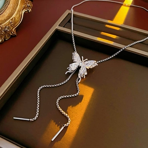Detailed view of silver butterfly pendant necklace with elegant dangling chains on a tray
