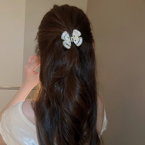 Dettaglio di un fermaglio per capelli a farfalla con madreperla e zirconi su capelli