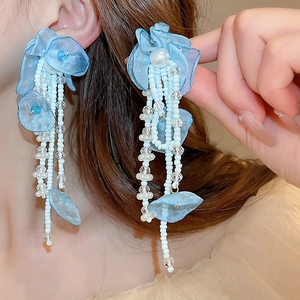 Gros plan d'une femme portant des boucles d'oreilles fleurs bleues à franges de perles