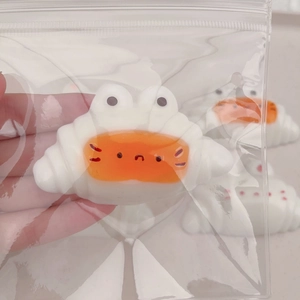 Macro shot of white crab-shaped resin charm in clear packaging for DIY decoration