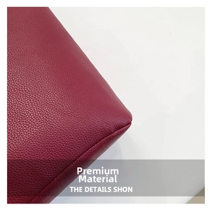 Detail shot of deep red lychee grain leather with neat stitching on a large tote bag