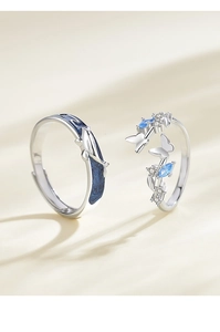 Macro shot of silver couple rings with blue whale and butterfly enamel details
