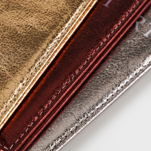 Macro detail showing colorful metallic embossed leather with precise white stitching