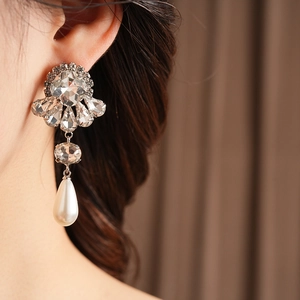 Close-up of vintage flower drop earring with crystals and a white pearl on a model