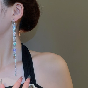 Macro side view of silver tassel earrings with zircon crystals worn by a model