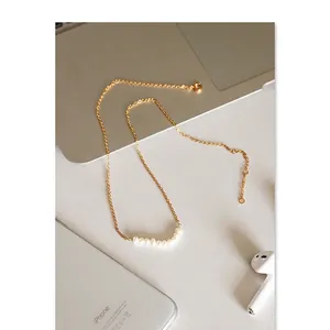 Elegant natural freshwater pearl necklace on a laptop and headphones background