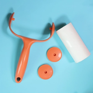 Orange and white lint roller set with handle and refill rolls on light blue background