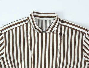 Dettaglio di una camicia a righe bianche e marroni con colletto e spalline a bottone