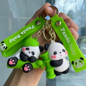 Detail of cute panda baby keychains with green silicone wrist straps and gold metal rings