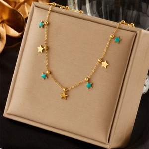 Close-up of a gold necklace with turquoise star pendants on a beige jewelry display box