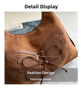 Close-up of retro brown suede tote featuring leather butterfly patch and lace-up eyelets