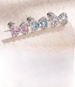 Detail of bow-shaped titanium steel studs with pink blue and white zircon stones