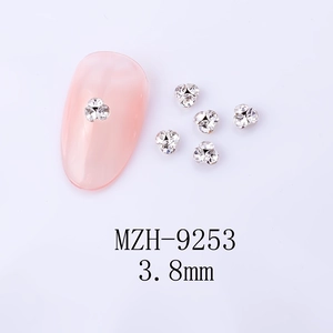 Détail de clous d'ongles floraux argentés de 3,8 mm avec strass sur ongle rose