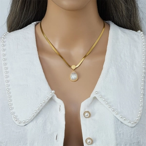 Elegant gold snake chain necklace with water drop pendant worn by a model
