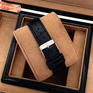 Close-up of black crocodile leather strap with silver metal buckle on a quartz man watch