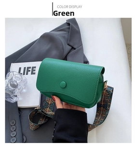 Detail of green pebble leather crossbody bag with ethnic patterned wide strap and buckle