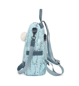Detail view of floral backpack featuring side pompom charm and blue leather straps