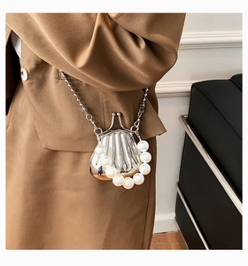 Detail der silbernen Metallic-Muscheltasche mit großem Perlenriff und Kette am Modell