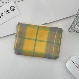 Gros plan d'un porte-monnaie en tissu à carreaux avec fermeture éclair sur un bureau