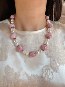 Detail of necklace with pink spotted ceramic beads and white pearls on a female model