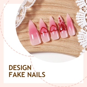 Faux ongles stiletto dégradé rose avec motifs cœurs rouges 3D sur support bois