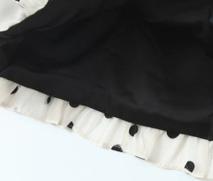 Détail de l'ourlet de robe double couche avec pois noirs sur mousseline beige