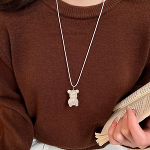 Close-up of translucent bear pendant necklace with iridescent finish on a cozy model