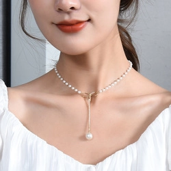 Detailed view of Y-shaped pearl necklace with golden chain and large drop pearl pendant