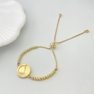 Detail of adjustable gold-beaded heart bracelet with round pendant tray and slide clasp