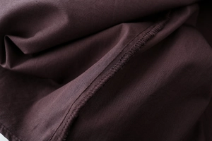 Macro shot of detailed overlock stitching and fabric texture on a dark brown cotton shirt