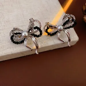 Elegant silver bow earrings with crystals and pearl on a textured vintage background