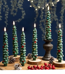 Detailed view of green Christmas tree LED candles with ornaments on a wooden table
