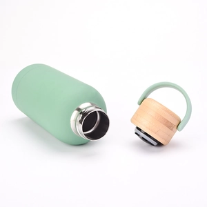 Detail of light green insulated bottle showing stainless steel interior and bamboo lid handle