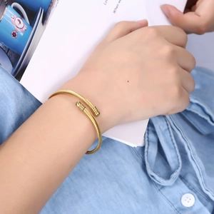 Close-up of a gold twisted cable open bangle featuring cylindrical end caps for women