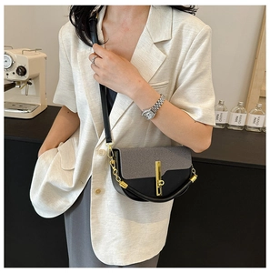 Detail of grey textured flap bag with golden vertical lock worn by model in a chic cafe