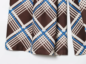 Gros plan du tissu écossais marron et bleu avec coutures fines sur le bord du short