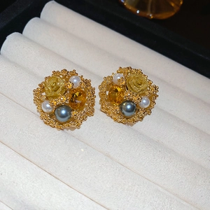 Macro shot of vintage gold floral earrings with amber and pearl beads in jewelry box