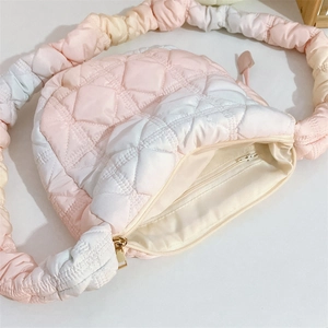 Detail of quilted gradient puffer bag showing zipper closure and beige interior lining
