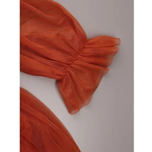 Detail view of the orange tulle ruffle sleeves and pleated texture on the maternity dress