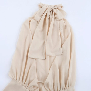 Close-up of halter neck with large bow tie and pleated cuffs on apricot chiffon dress