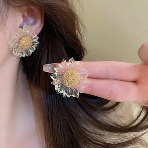 Macro shot of transparent flower earrings with golden core details on ear
