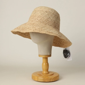 Detail of hand-woven beige raffia sun hat with hollow pattern and windproof strap